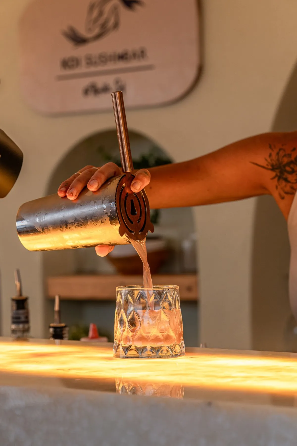 Barmen bakır shaker'dan kokteyli kesme bardağa döküyor.